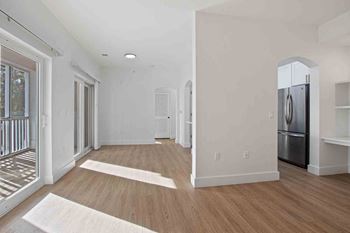 a living room with a refrigerator and a door into a kitchen